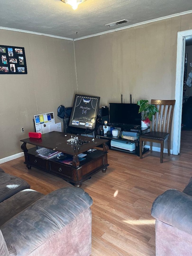 living room with crown molding, wood finished floors, and visible vents