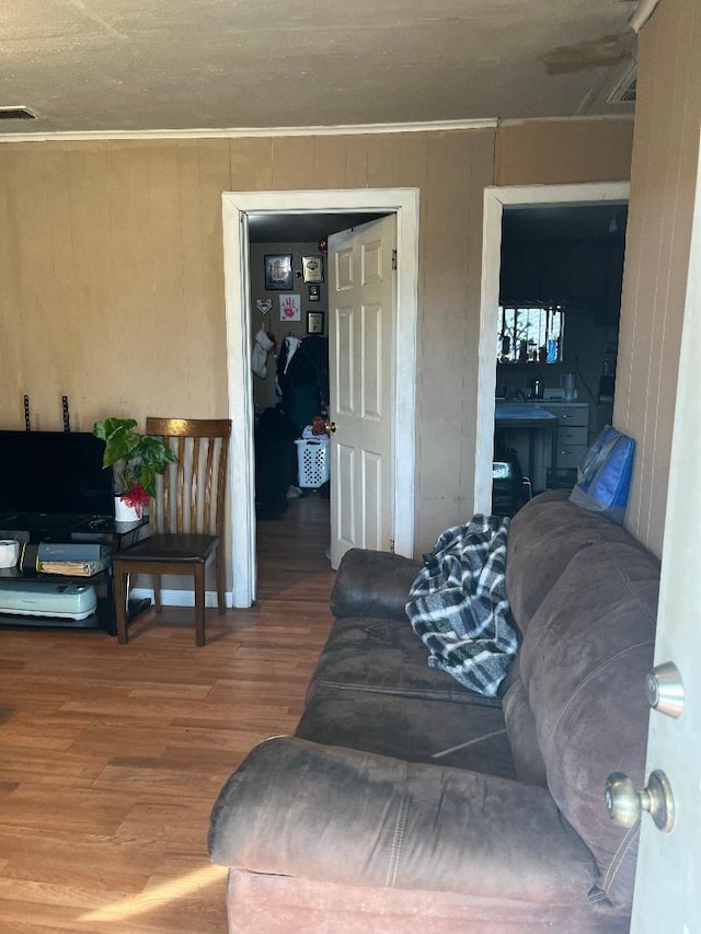 living room with visible vents, crown molding, and wood finished floors