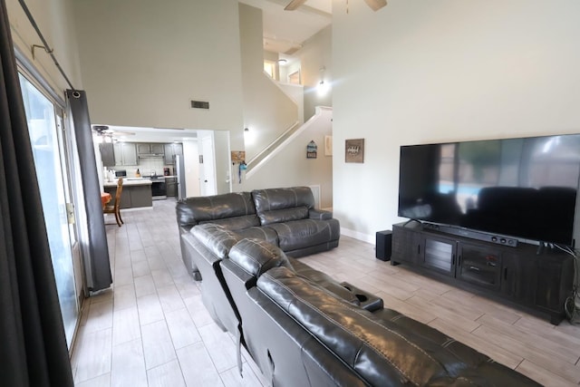 living room featuring ceiling fan and a high ceiling