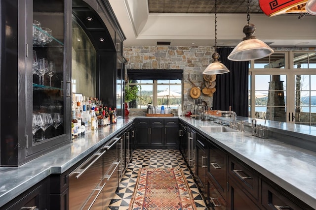 bar with decorative light fixtures, sink, and stainless steel counters