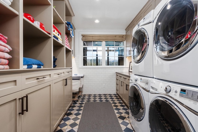 clothes washing area with stacked washing maching and dryer, tile walls, and washing machine and dryer