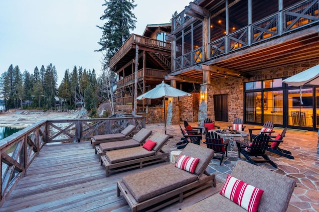 view of patio / terrace with a wooden deck and an outdoor living space with a fire pit