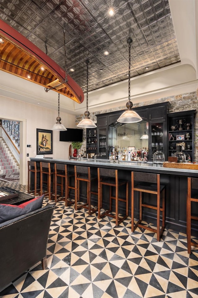 bar with crown molding and hanging light fixtures