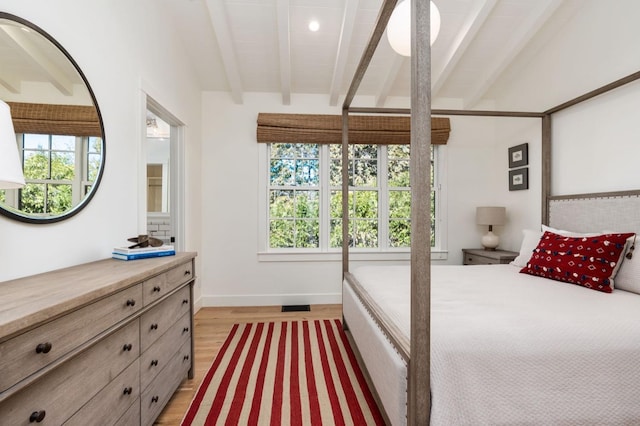 bedroom featuring multiple windows, light hardwood / wood-style flooring, and lofted ceiling with beams