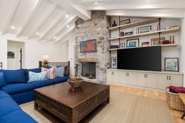 living room with a stone fireplace, lofted ceiling with beams, and light hardwood / wood-style flooring