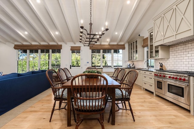 dining room featuring vaulted ceiling with beams, sink, an inviting chandelier, and light hardwood / wood-style flooring