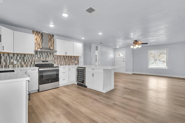 kitchen with white cabinetry, stainless steel range with electric cooktop, beverage cooler, and wall chimney exhaust hood