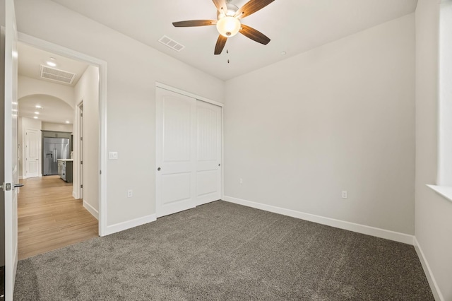 unfurnished bedroom with ceiling fan, built in refrigerator, carpet floors, and a closet