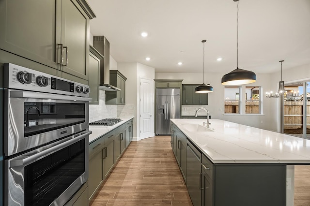 kitchen featuring hanging light fixtures, sink, a large island with sink, and appliances with stainless steel finishes