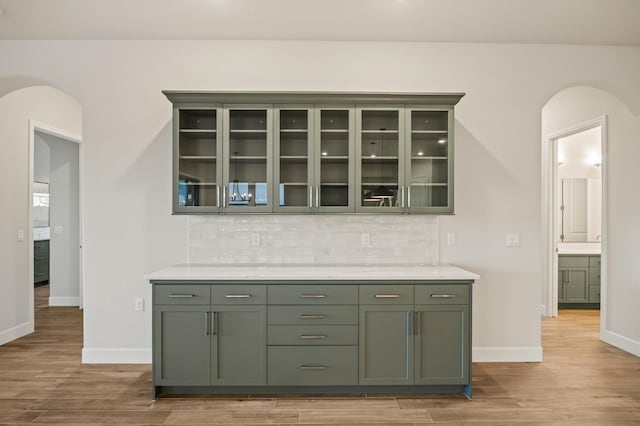 bar with light hardwood / wood-style floors and decorative backsplash