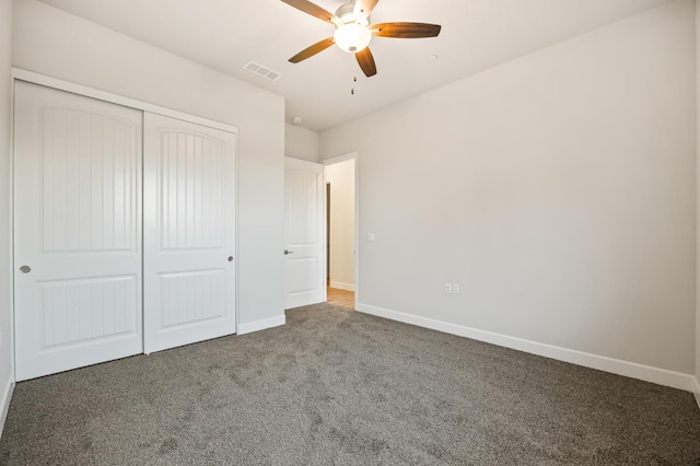 unfurnished bedroom with ceiling fan, dark carpet, and a closet