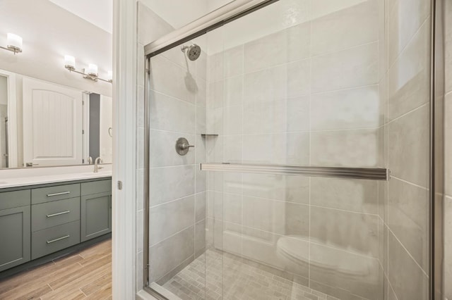 bathroom with vanity, a shower with shower door, and wood-type flooring