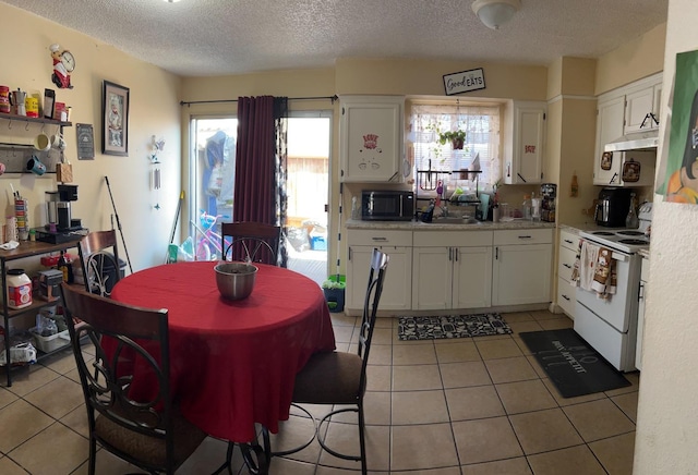 kitchen featuring light tile patterned floors, electric stove, light countertops, and white cabinetry