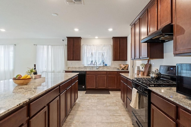 kitchen with sink, light stone counters, and black appliances