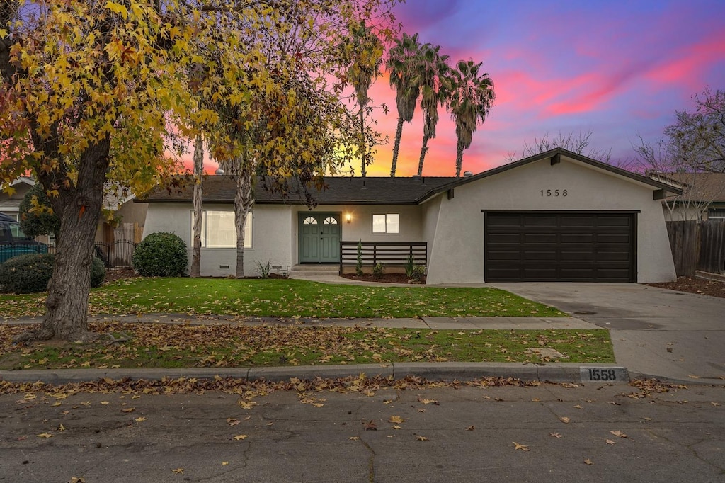 ranch-style home with a garage and a yard