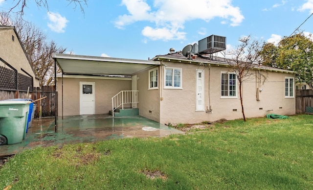 back of property featuring stucco siding, crawl space, central AC, a yard, and fence