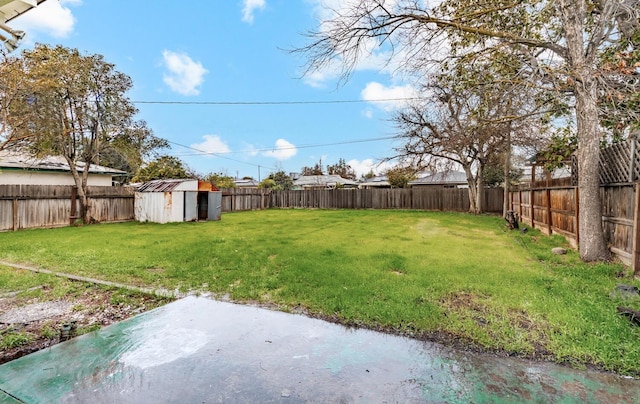 view of yard with a storage shed, a fenced backyard, and an outbuilding