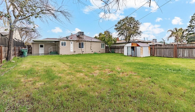 rear view of house featuring a storage shed, a lawn, and central air condition unit