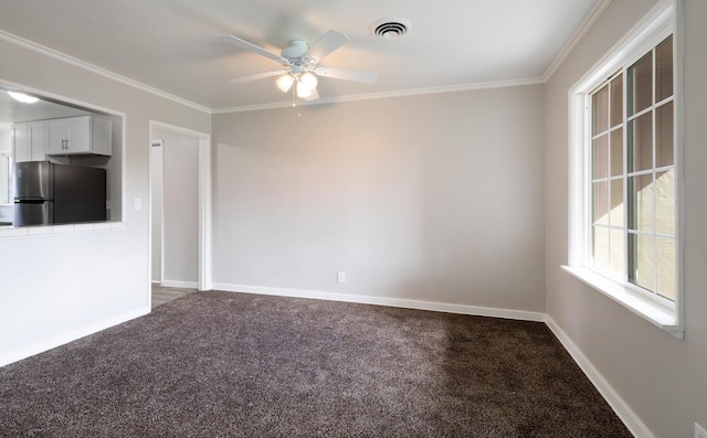 carpeted empty room with ornamental molding, ceiling fan, visible vents, and baseboards