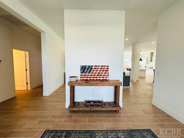 corridor featuring baseboards and wood tiled floor