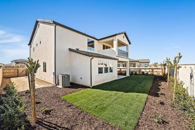 back of property with a balcony, a lawn, and central air condition unit