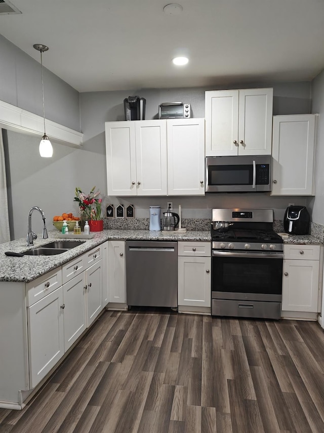 kitchen with appliances with stainless steel finishes, decorative light fixtures, and white cabinets