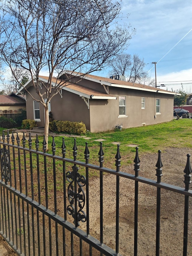 view of home's exterior featuring a lawn, fence, and stucco siding