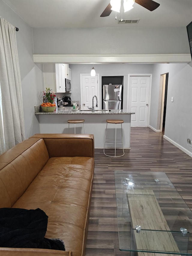 living area featuring dark wood-style floors, baseboards, visible vents, and a ceiling fan