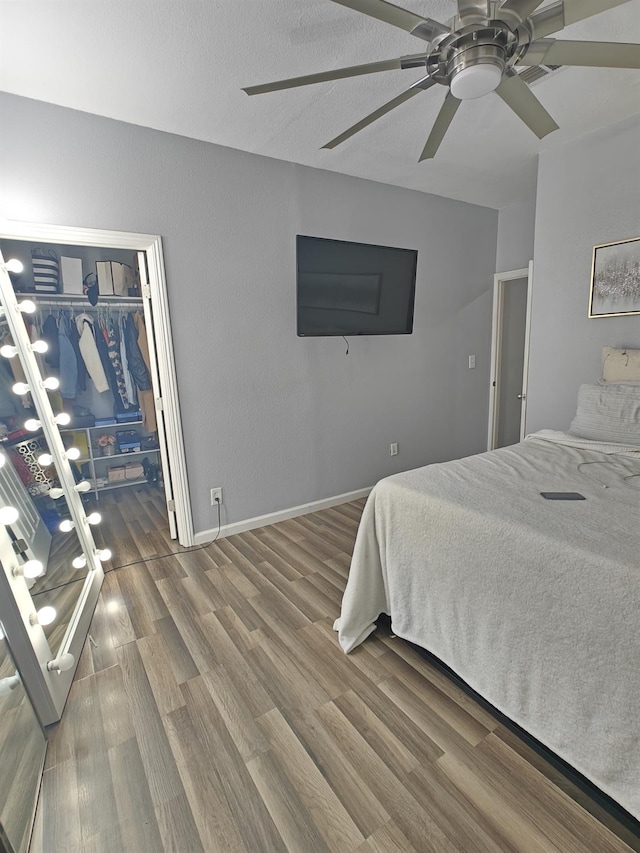 bedroom with ceiling fan, a closet, wood finished floors, and baseboards