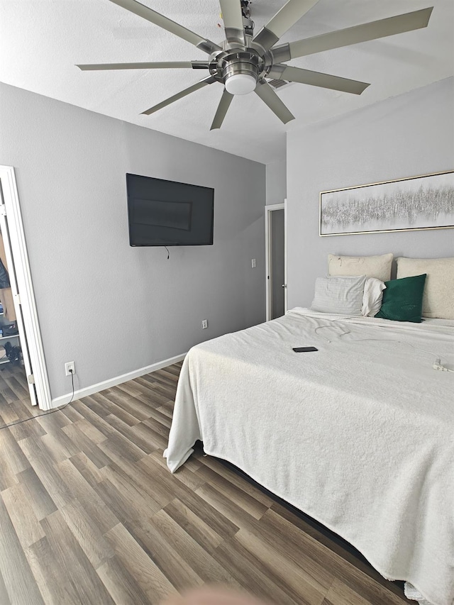 bedroom with ceiling fan, wood finished floors, and baseboards