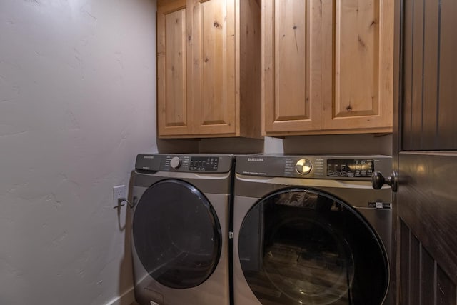 clothes washing area featuring cabinet space and washer and clothes dryer