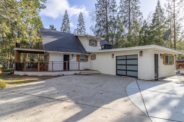 view of front of house featuring driveway, central AC unit, roof with shingles, and an attached garage