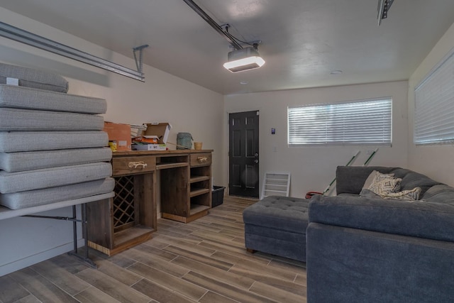 living area with a garage, visible vents, and wood tiled floor