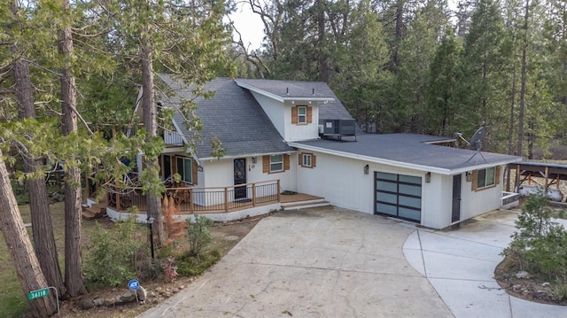 view of front of house with driveway, a shingled roof, an attached garage, and central air condition unit