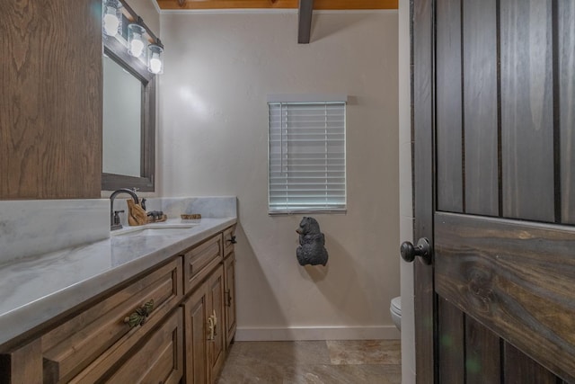 bathroom with toilet, baseboards, and vanity