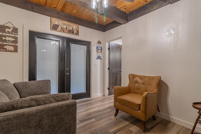 living area featuring french doors, beam ceiling, wood finished floors, wooden ceiling, and baseboards