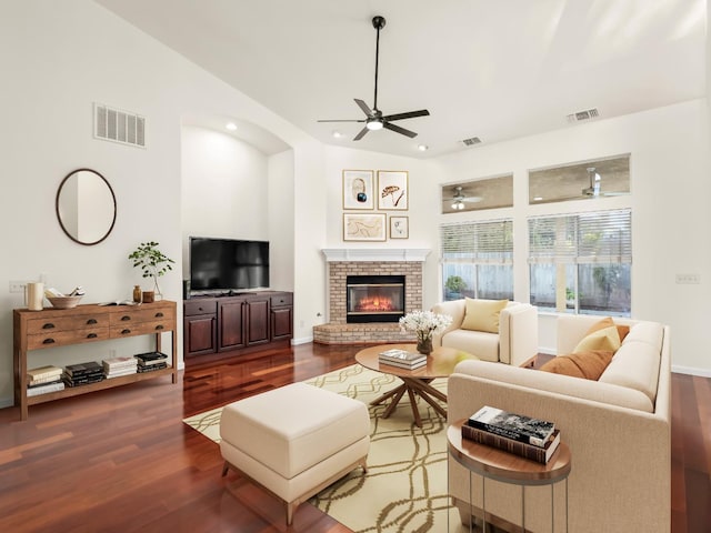 living room with wood-type flooring, a brick fireplace, and ceiling fan