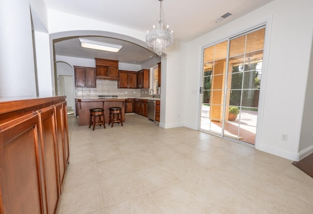 kitchen with a kitchen bar, a center island, hanging light fixtures, stainless steel dishwasher, and decorative backsplash