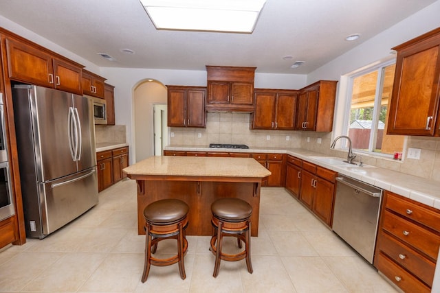 kitchen featuring sink, appliances with stainless steel finishes, a kitchen breakfast bar, a center island, and tasteful backsplash