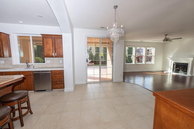 kitchen with sink, ceiling fan with notable chandelier, dishwasher, decorative backsplash, and decorative light fixtures