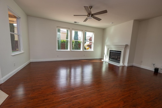 unfurnished living room featuring dark wood-type flooring and ceiling fan