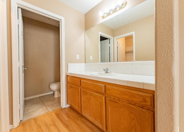 bathroom with wood-type flooring, vanity, and toilet