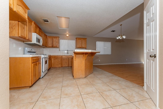 kitchen with light tile patterned floors, white appliances, a breakfast bar area, a center island, and tile counters