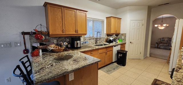 kitchen with light tile patterned floors, sink, stainless steel dishwasher, light stone countertops, and decorative backsplash