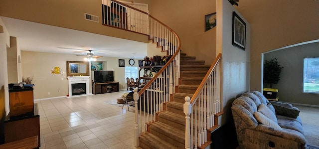 staircase with ceiling fan and a towering ceiling