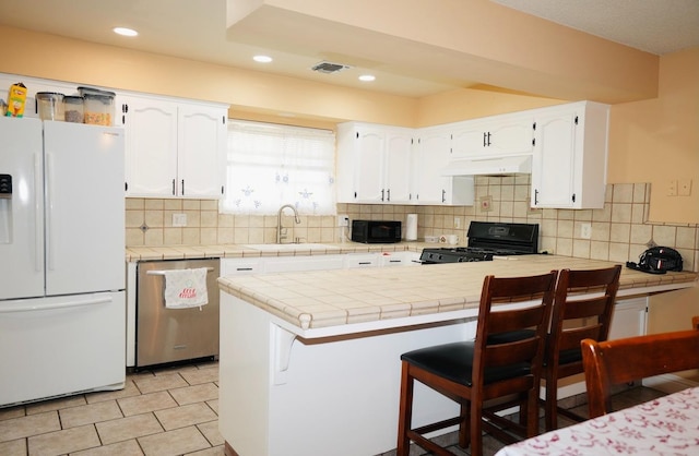 kitchen featuring black appliances, white cabinetry, sink, a breakfast bar area, and kitchen peninsula