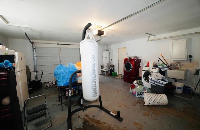 garage with water heater, sink, white refrigerator, a garage door opener, and washer and clothes dryer