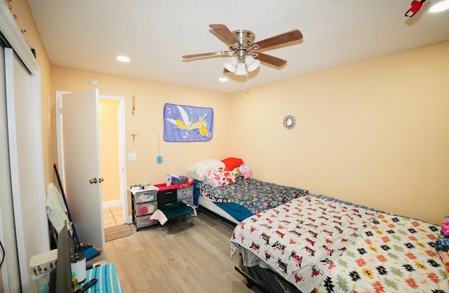 bedroom with a closet, a textured ceiling, ceiling fan, and light hardwood / wood-style flooring