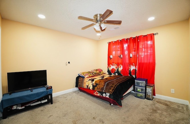 carpeted bedroom featuring ceiling fan and a textured ceiling