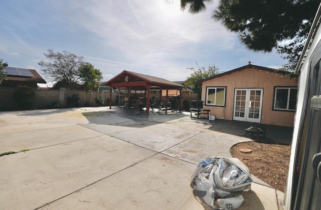 view of patio / terrace featuring french doors, a gazebo, an outbuilding, and a fire pit